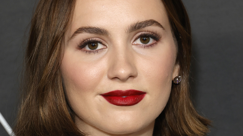 Maude Apatow smiling for photo with red lipstick