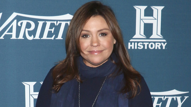 Rachael Ray posing in a scarf and dark colored outfit