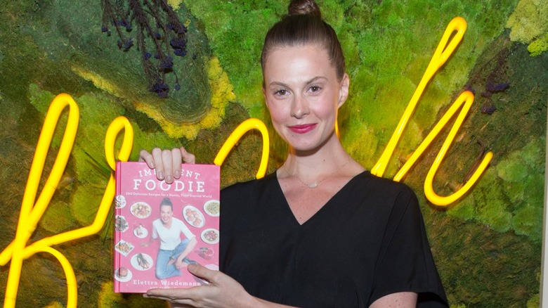 Elettra Rossellini Wiedemann holding her cookbook