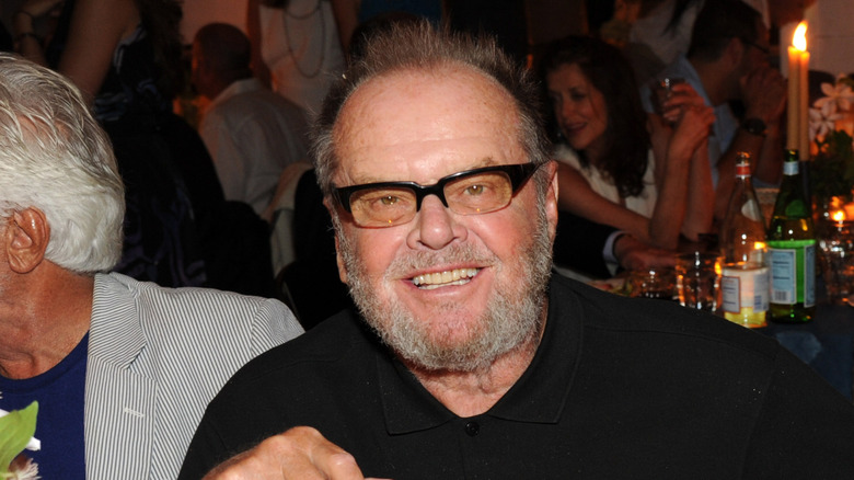 Jack Nicholson wearing glasses and smiling at a table.