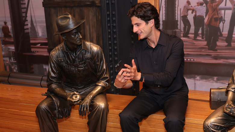 Jack Schlossberg posing with statues at the Empire State Building.
