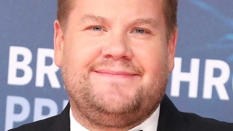 James Corden with small smile, slicked back hair