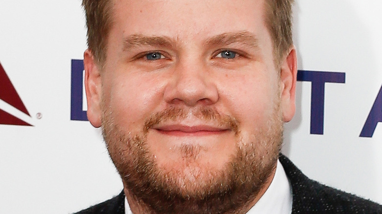 James Corden grins as he poses in a suit on the red carpet