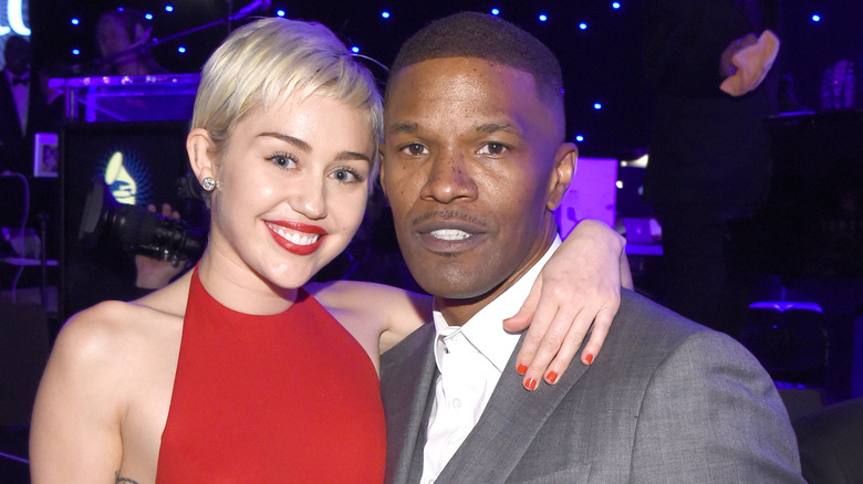 Miley Cyrus with arm around Jamie Foxx