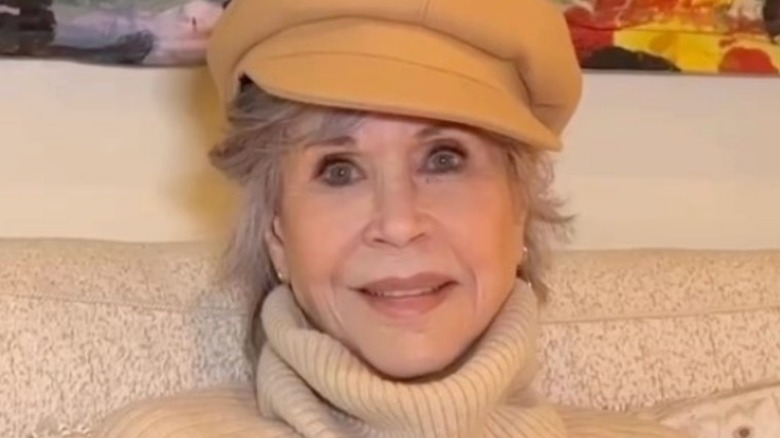 Jane Fonda smiling in yellow peaked cap
