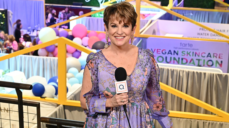 Jane Treacy presenting in a purple floral-print dress