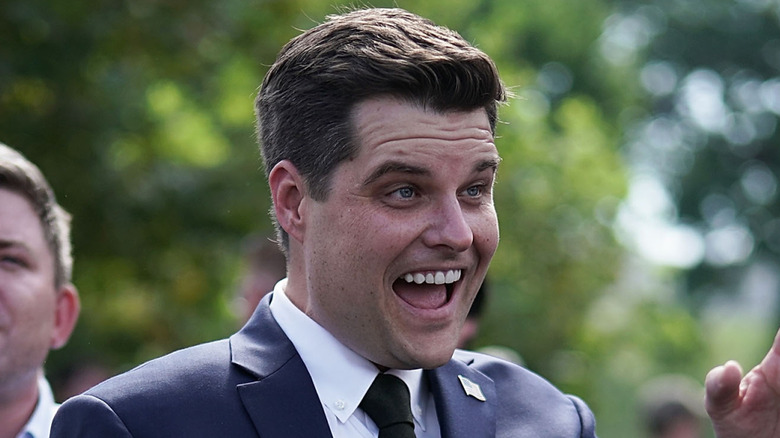 Matt Gaetz smiles and waves to someone animatedly.