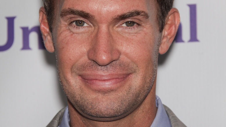 Jeff Lewis smirking and looking at camera while posing at an event 