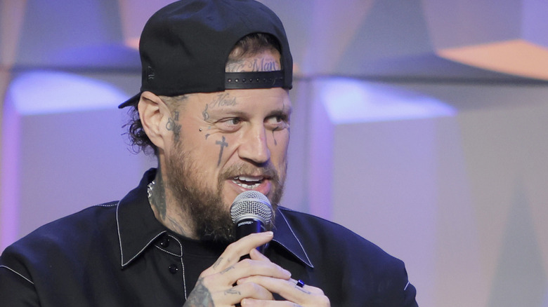 Jelly Roll wearing backwards cap talking into microphone