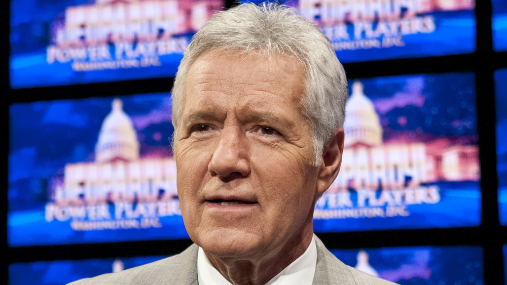 Former Jeopardy! host Alex Trebek standing in front of the game board