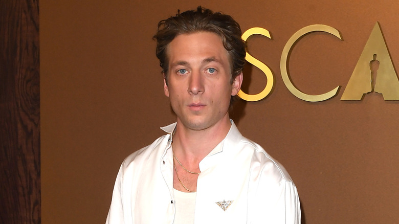 Jeremy Allen White posing in front of a gold Oscars background