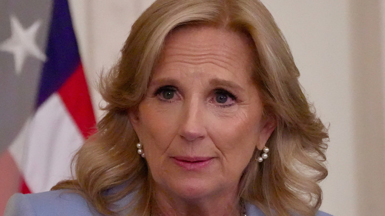 Jill Biden with styled blonde hair and pearl earrings looking tearful and concerned