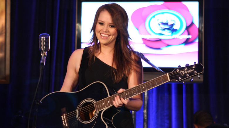 Jane Carrey sings and plays guitar on stage in 2007