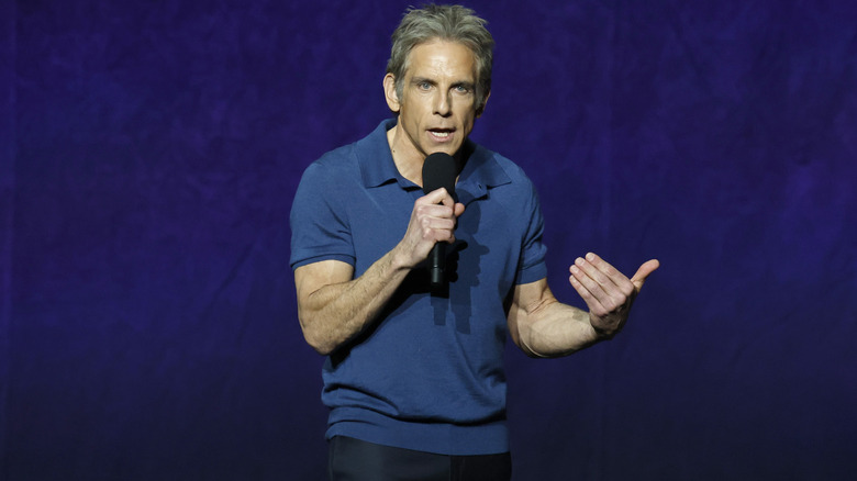 Ben Stiller wearing a blue polo shirt and speaking on stage at a promotional event for "Focker-in-Law."