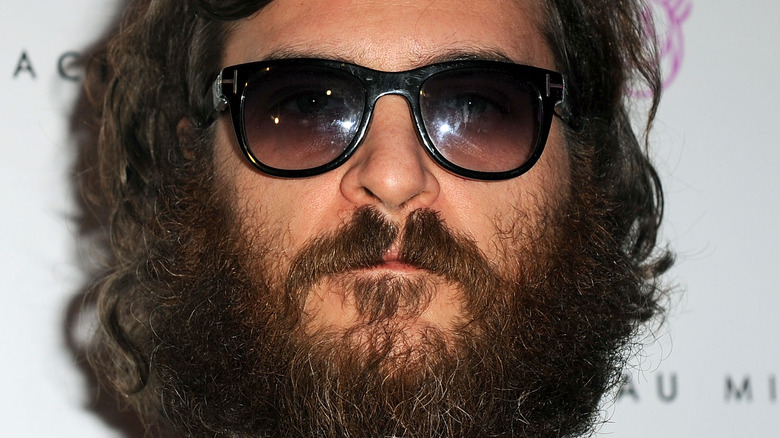 Joaquin Phoenix wears a beard and sunglasses