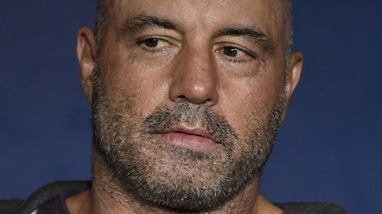 Joe Rogan holds a microphone near his chin