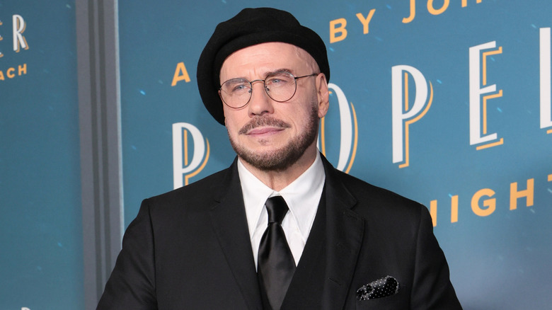 John Travolta posing in a beret and a black suit at a screening of 