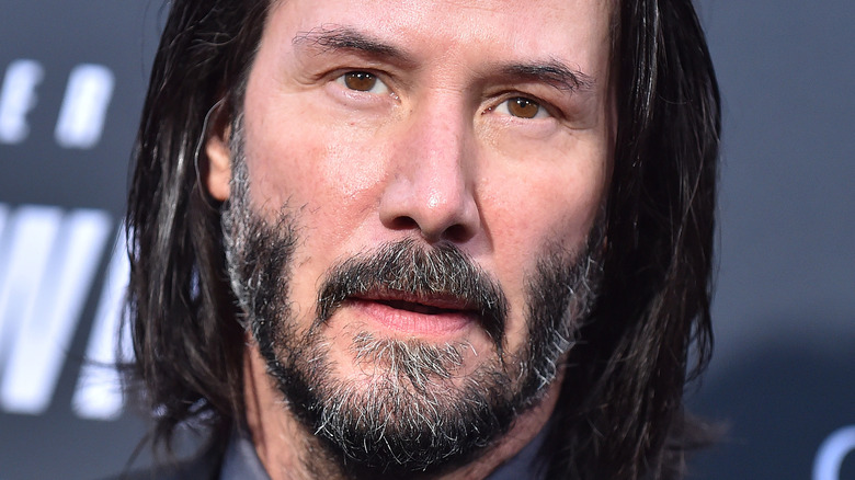 Keanu Reeves poses in a dark suit.