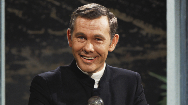 Johnny Carson smiling in front of a microphone.