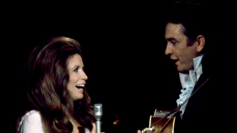 June Carter and Johnny Cash facing each other while singing onstage.
