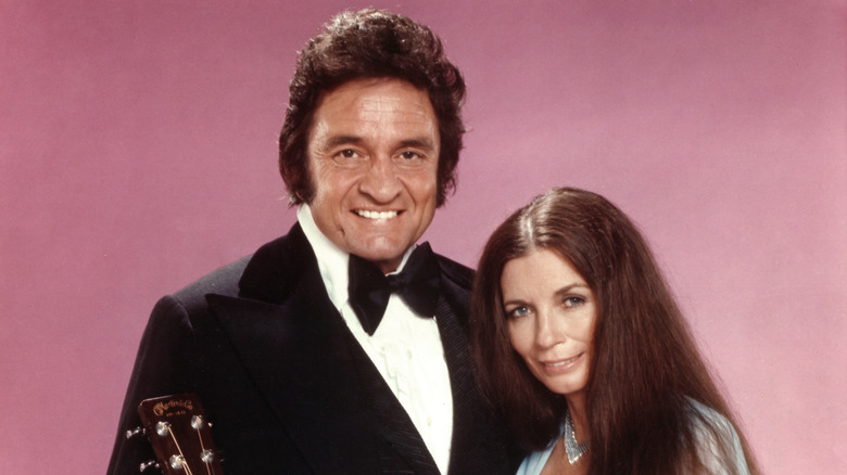 Johnny Cash and June Carter Cash posing in front of a pink background.