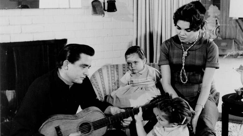 Johnny Cash and Vivian Liberto sitting in a living room with two of their young daughters.