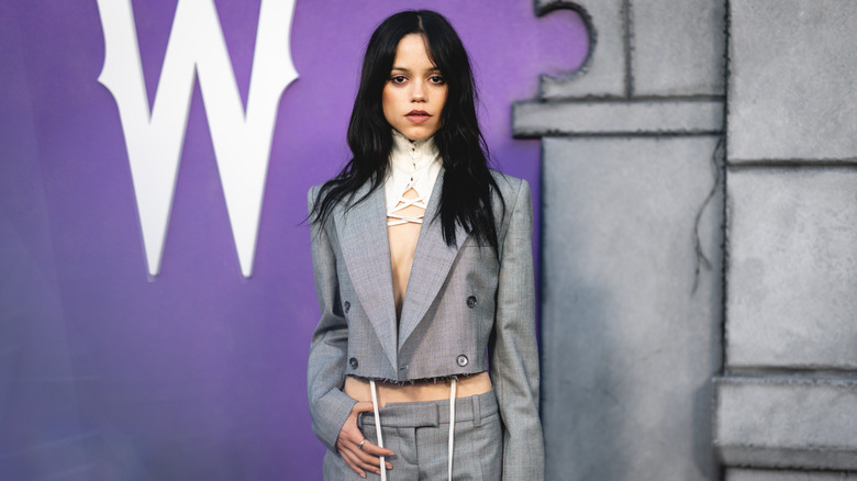 Jenny Ortega posing in a gray suit.