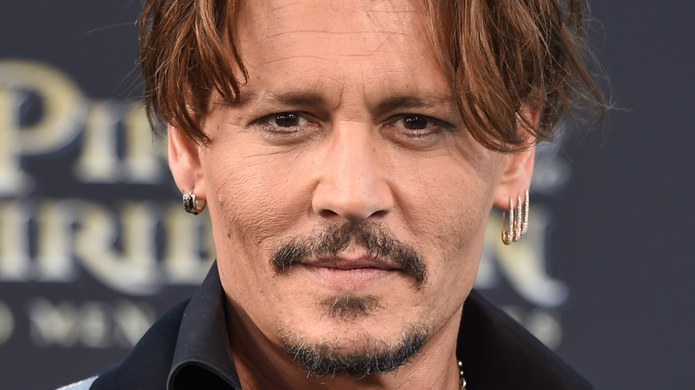 Johnny Depp posing diamond safety pin earrings
