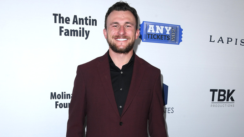 Johnny Manziel smiling in a red jacket