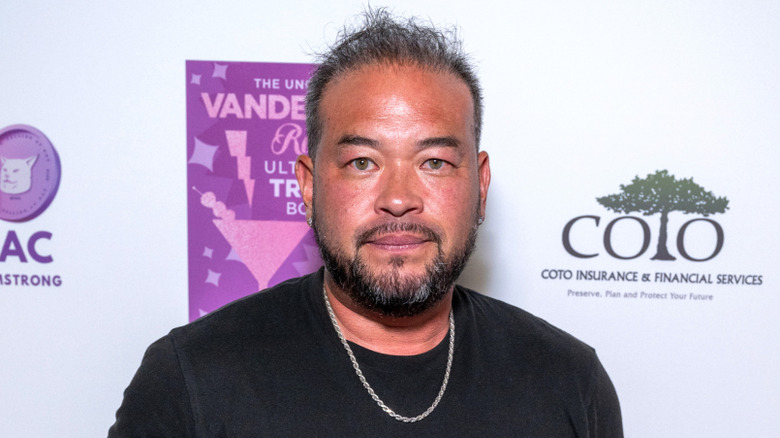 Jon Gosselin poses in a black T-shirt and silver chain in 2024