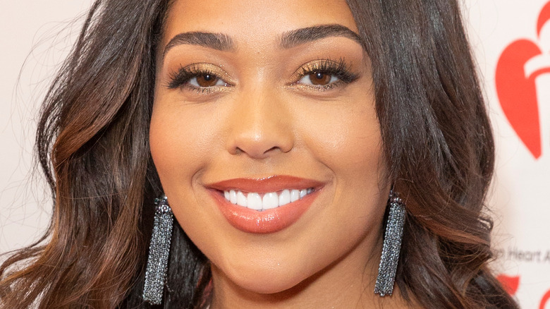 Jordyn Woods smiles in a red dress