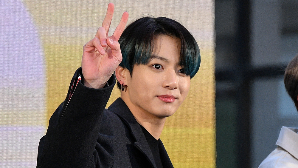 Jungkook smiling and giving a peace sign