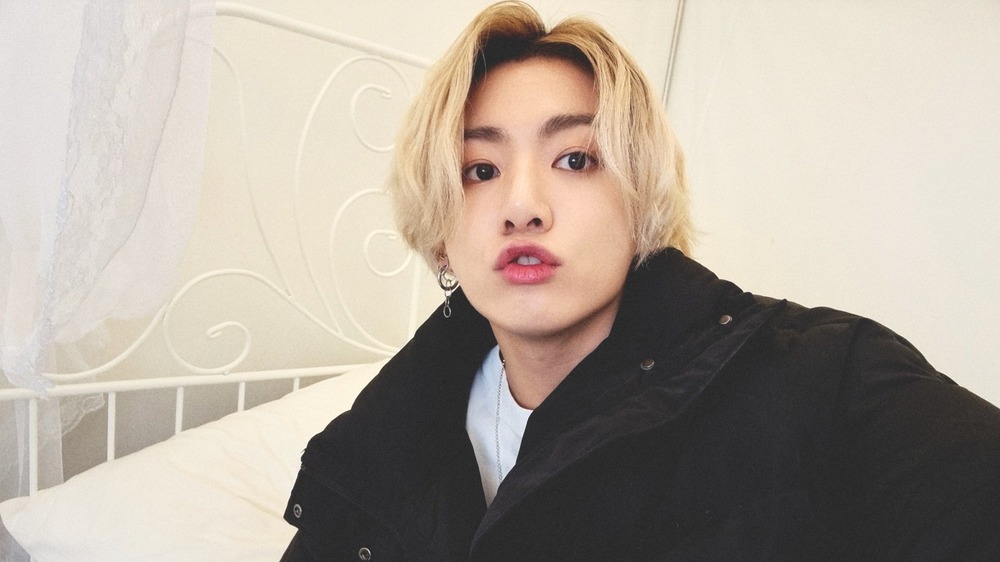Jungkook posing for a selfie on a white bed
