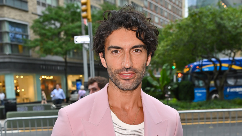 Justin Baldoni poses outside in a pink blazer.
