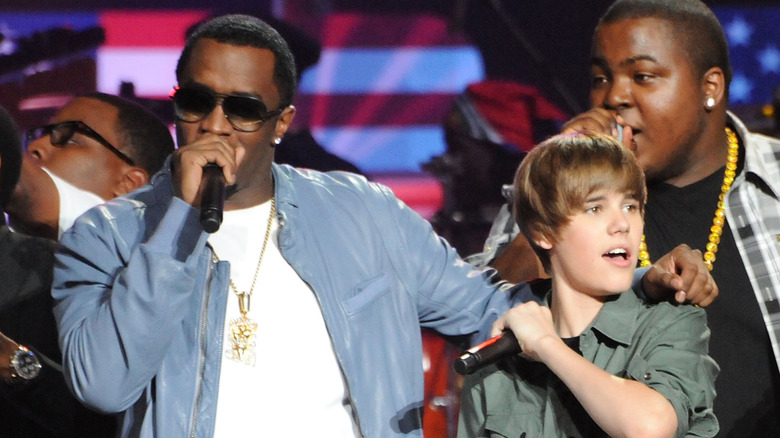 Diddy singing with his arm around a teenage Justin Bieber