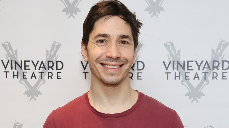 Justin Long smiles in a red shirt