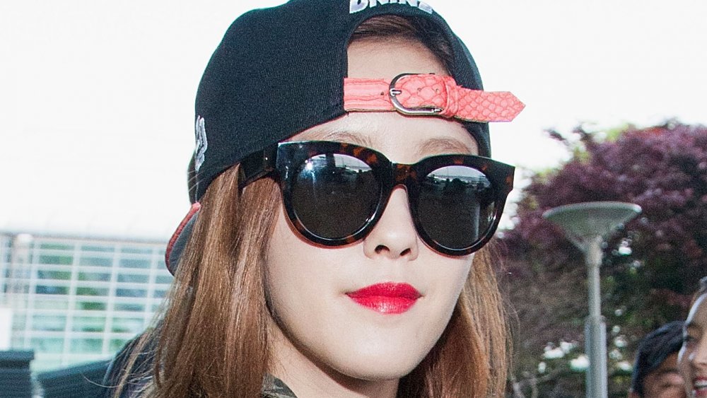 Hyomin of T-ARA in a black backwards hat and sunglasses