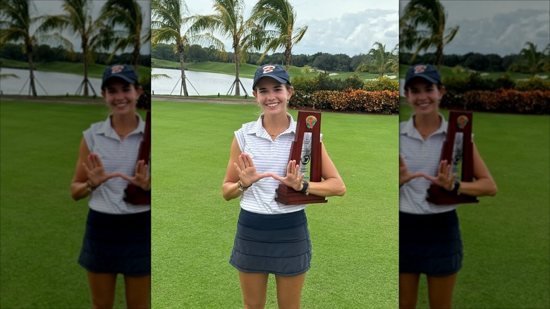 Kai Trump holding a trophy and making a W sign