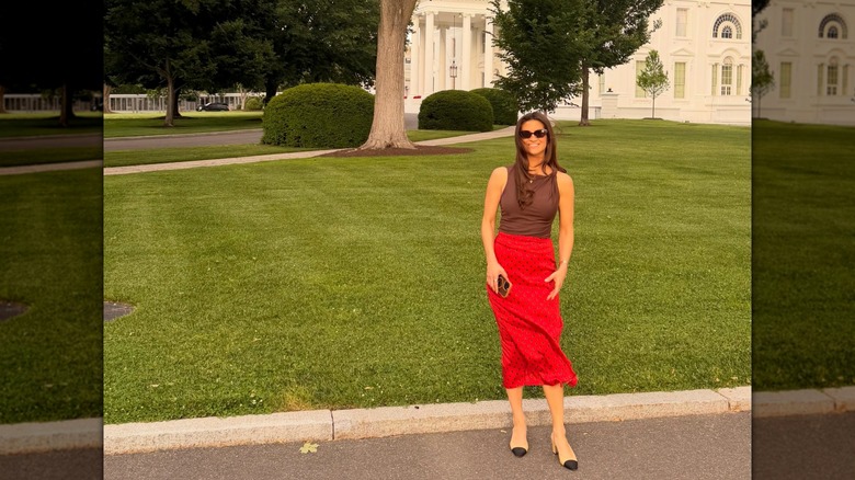 Kaitlan Collins standing in front of green lawn smiling.