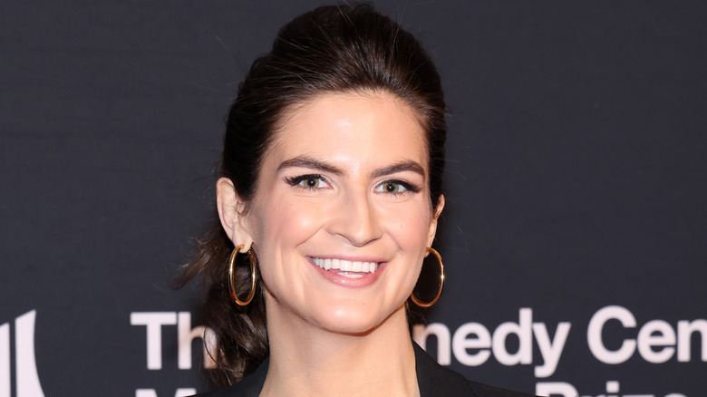 Kaitlan Collins smiling with big gold hoop earrings.