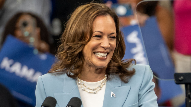 Kamala Harris smiling on stage in front of microphone