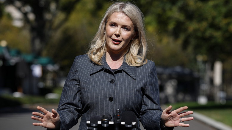 Karoline Leavitt standing with her hands splayed while speaking to reporters outside