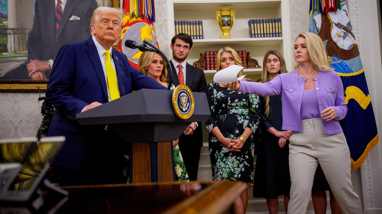 Karoline Leavitt gives paper to Trump