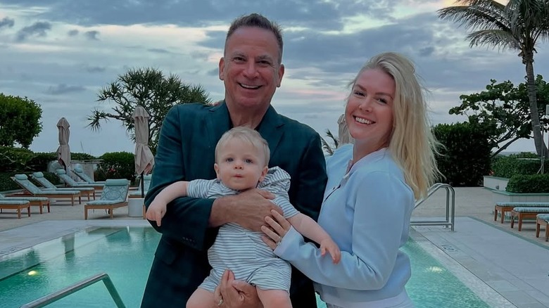 Karoline Leavitt smiling poolside with Nicholas Riccio, who holds their son, Niko