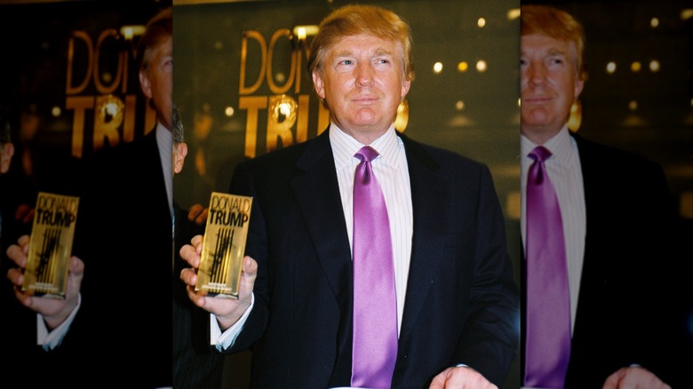 Donald Trump posing with a bottle of his cologne.