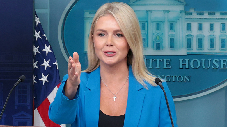 Karoline Leavitt speaking in a blue blazer and black shirt while at a press briefing.