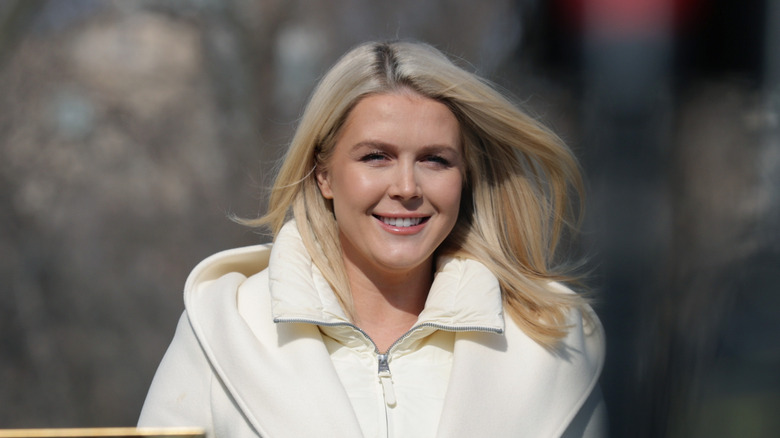 Karoline Leavitt smiling with teeth while walking in a white coat