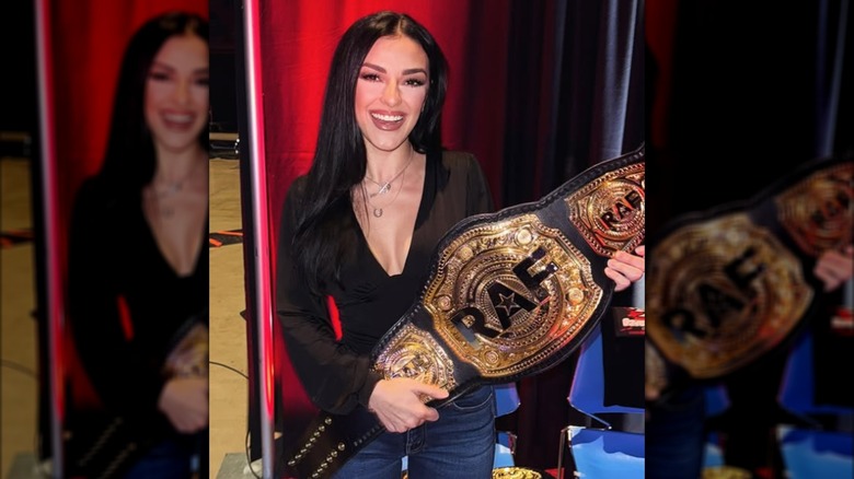 Alexis Wilkins posing with a belt at a Real American Freestyle tournament.