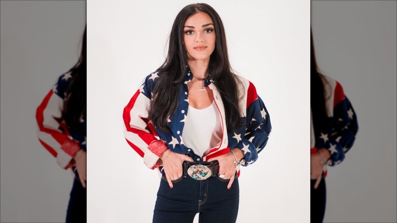 Alexis Wilkins wearing an American flag shirt with a big belt buckle.