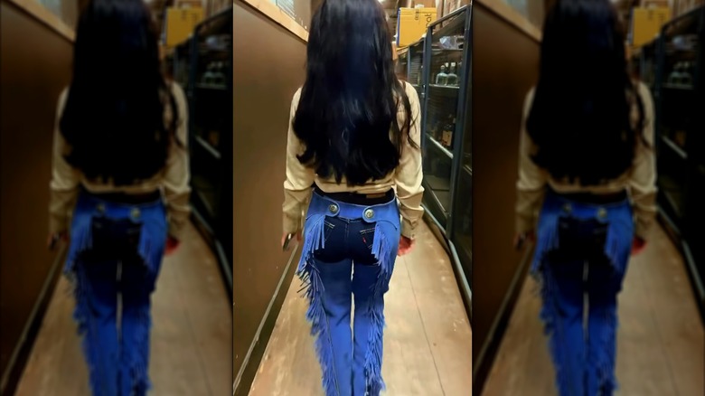 Alexis Wilkins walking into a performance wearing chaps.